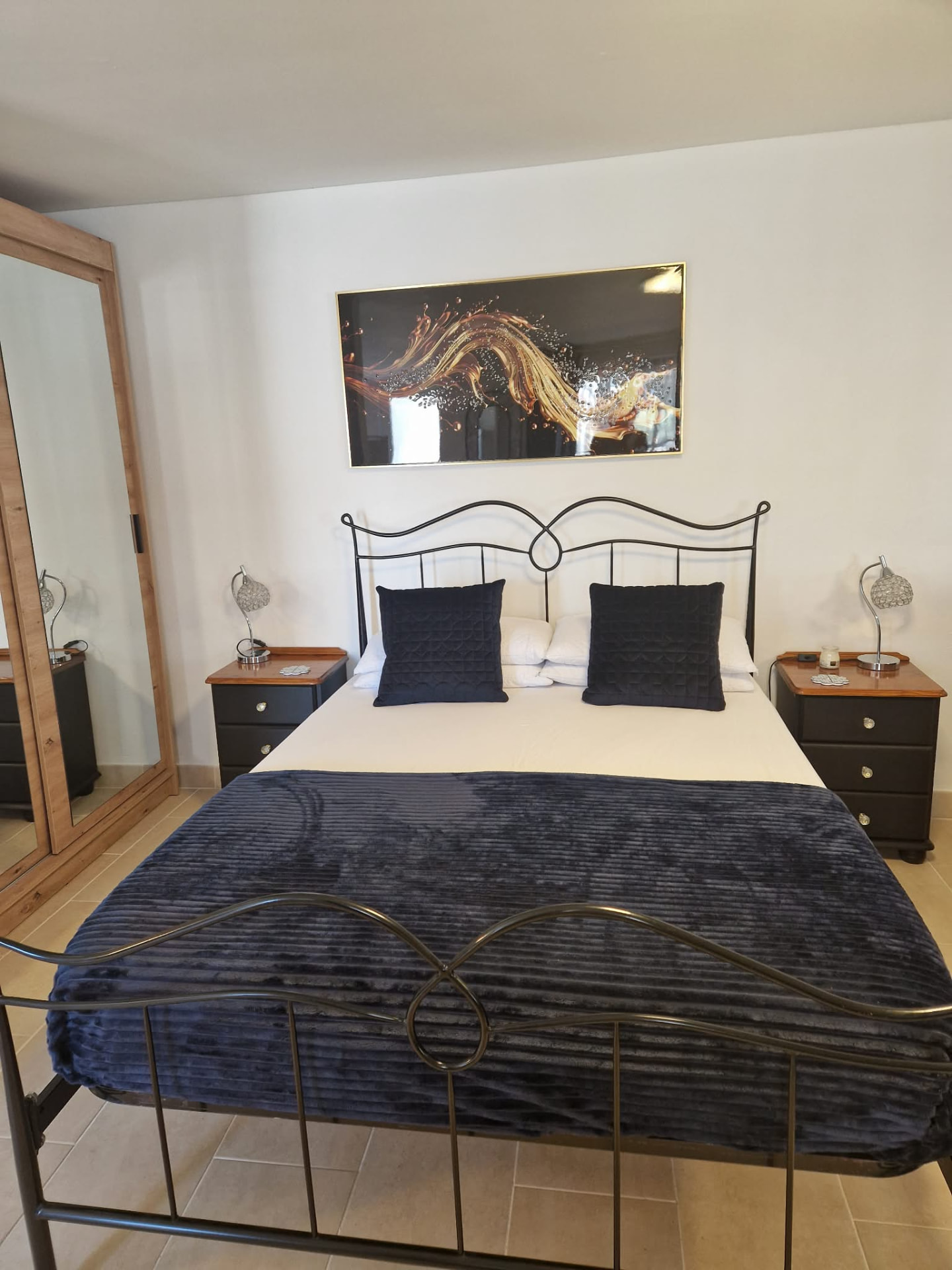 Large double bedroom with iron bedstead, bedside tables and full-length mirror