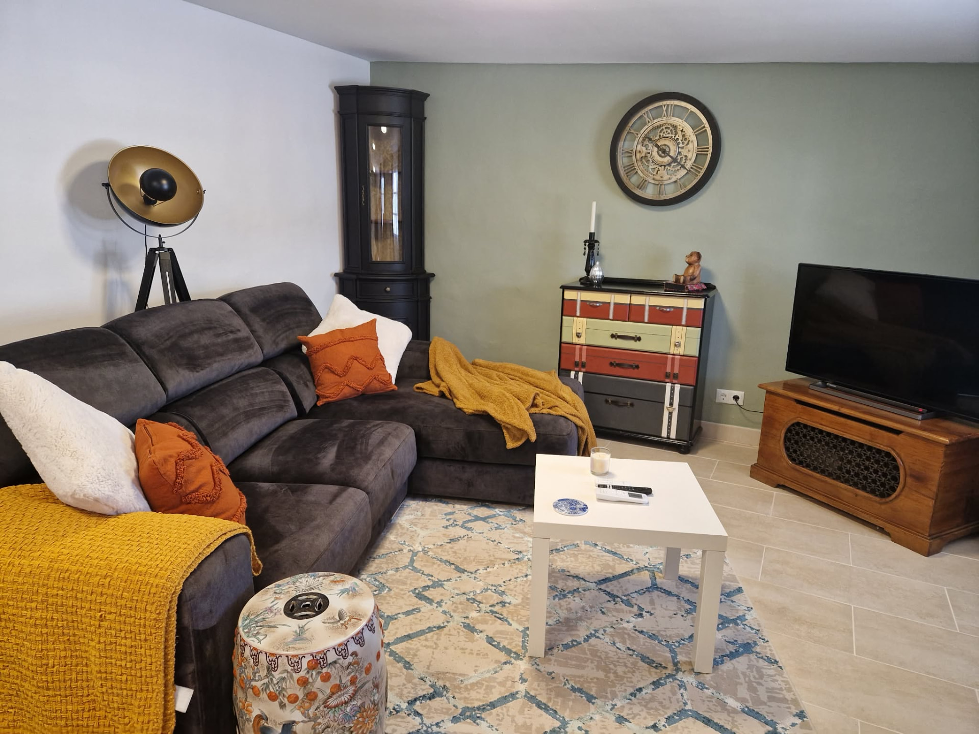 Living area with large corner sofa, smart TV and sage green wall