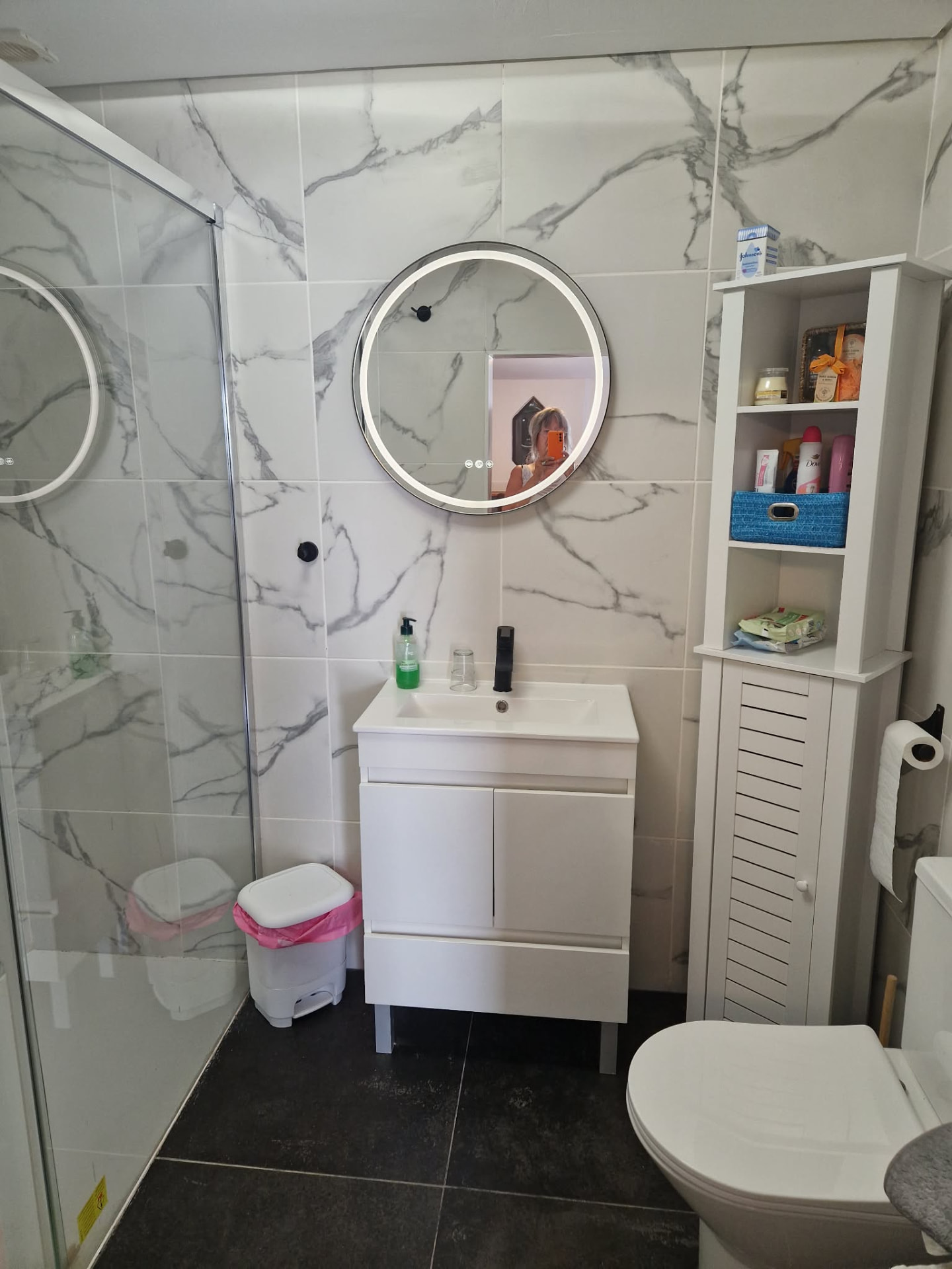 Marble-tiled shower room with vanity unit, lit mirror and WC
